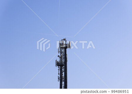 Telecommunications tower with cellular antennas and repeaters against a clear blue sky Telecommunications tower with cellular antennas and repeaters against a clear blue sky 99486951