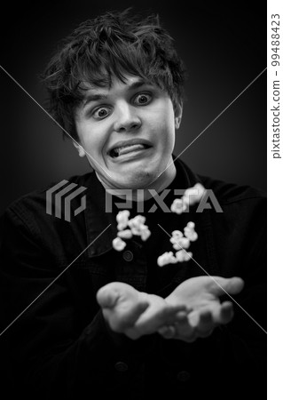 portrait of crazy young man throwing up popcorn portrait of crazy young man throwing up popcorn 99488423