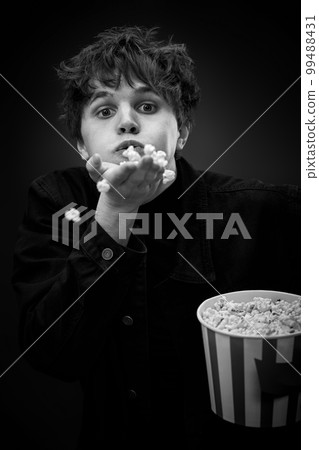 portrait of crazy young man throwing up popcorn 99488431