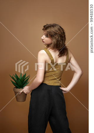 woman with stylish hairstyle posing with plant in pot 99488530