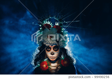 Woman with mexican skull halloween makeup on face. Day of the dead aka Dia de los Muertos and halloween party concept. Woman with mexican skull halloween makeup on face. Day of the dead aka Dia de los Muertos and halloween party concept. 99490256