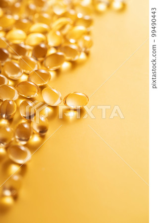 Omega 3 or Vitamin D pills. Fish oil gel capsules on yellow background in angel view. Omega 3 or Vitamin D pills. Fish oil gel capsules on yellow background in angel view. 99490443