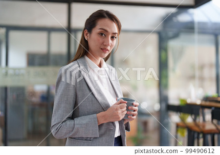 Female employee with coffee at workplace. Businesswoman preparing economic report. Female employee with coffee at workplace. Businesswoman preparing economic report. 99490612