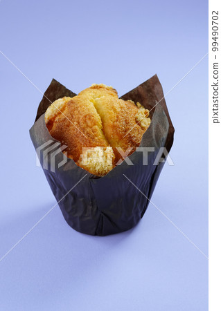 The golden brown muffin is isolated on a plain, light-coloured background. Freshly baked dessert close-up, vertical photo, template with copy space. 99490702