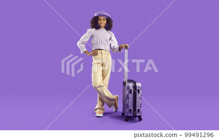 Happy African American child with holiday baggage standing on purple studio background 99491296