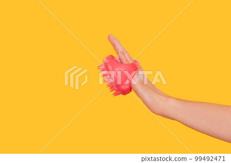 Massager for the scalp in pink color in female hand against yellow background 99492471