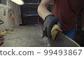 Male worker of ski service workshop doing sharpening and repair of skis. Sharpening ski edges with a manual side-edge tuning tool fitted with a diamond stone. Theme repair of ski curb 99493867