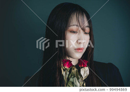A woman in a black dress with dried flowers and a green background A woman in a black dress with dried flowers and a green background 99494869