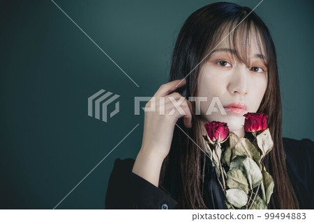 A woman in a black dress with dried flowers and a green background A woman in a black dress with dried flowers and a green background 99494883