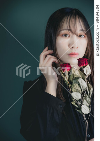 A woman in a black dress with dried flowers and a green background A woman in a black dress with dried flowers and a green background 99494884