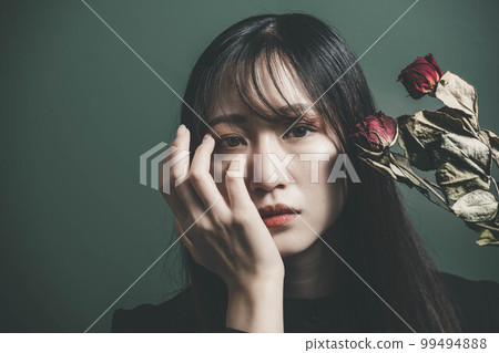 一個穿著黑色連衣裙、乾花和綠色背景的女人 99494888