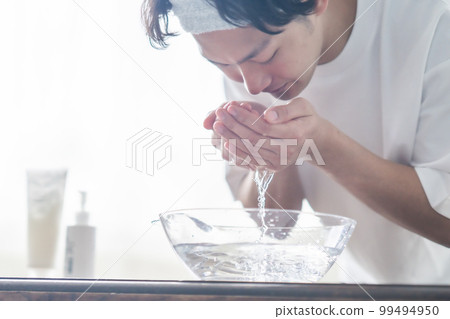 A young man wearing a hair band and washing his face 99494950