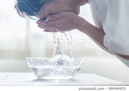 A young man wearing a hair band and washing his face 99494955