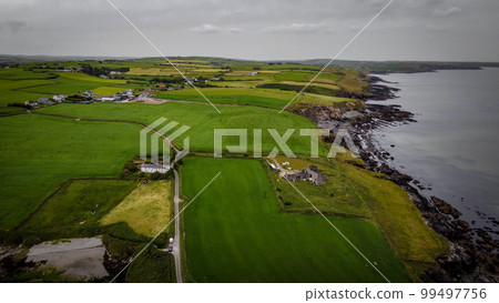 Green fields on the hills, top view. The countryside of Ireland on a cloudy day. The coast of Clonakilty Bay at low tide. Green grass field under cloudy sky Green fields on the hills, top view. The countryside of Ireland on a cloudy day. The coast of Clonakilty Bay at low tide. Green grass field under cloudy sky 99497756