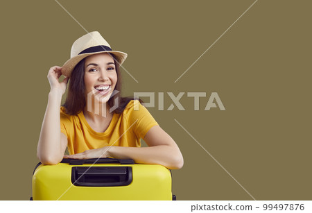 Portrait of cheerful young female tourist with suitcase smiling happily on brown background. Portrait of cheerful young female tourist with suitcase smiling happily on brown background. 99497876