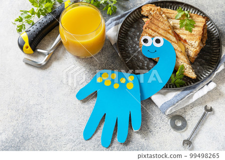 Father's day dinosaur card and breakfast for dad on gray stone table. 99498265