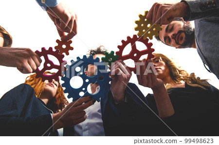 Business team connect pieces of gears. Teamwork, partnership and integration concept Business team connect pieces of gears. Teamwork, partnership and integration concept 99498623