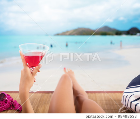Girl relaxes at the beach with a cold drink Girl relaxes at the beach with a cold drink 99498658