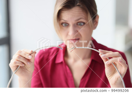 Woman in office with broken network cable in her hands 99499206