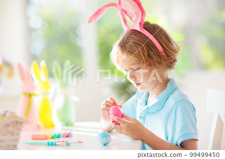 Kids on Easter egg hunt. Children dye eggs. 99499450