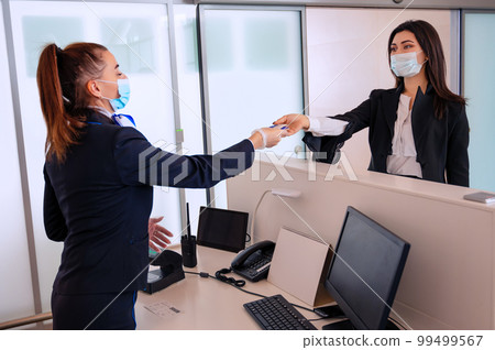 Passenger giving his documents for check-in to airport manager by counter Passenger giving his documents for check-in to airport manager by counter 99499567