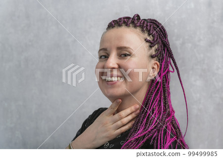 Portrait of cheerful young caucasian woman with pink artificial dreadlocks on gray background. Portrait of cheerful young caucasian woman with pink artificial dreadlocks on gray background. 99499985