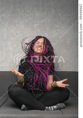 Emotional girl with dreadlocks is nervous and waves her head. Portrait of angry or laughing woman. Vertical frame. 99499987