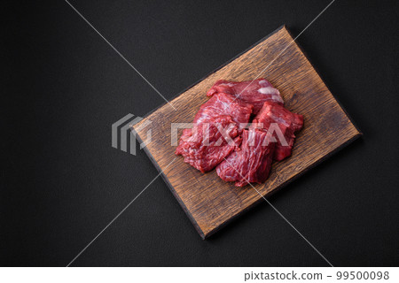 Raw beef cut into several pieces on a wooden cutting board 99500098