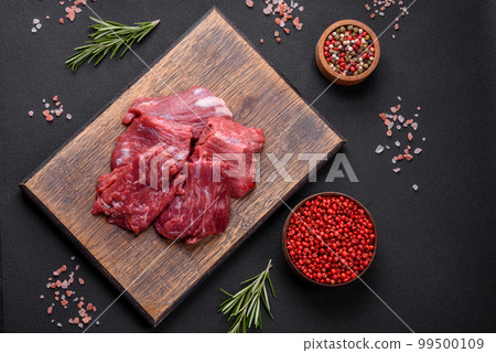 Raw beef cut into several pieces on a wooden cutting board Raw beef cut into several pieces on a wooden cutting board 99500109