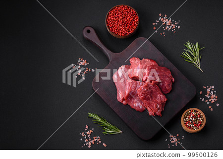 Raw beef cut into several pieces on a wooden cutting board 99500126