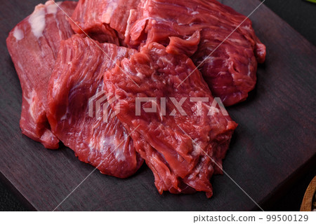 Raw beef cut into several pieces on a wooden cutting board Raw beef cut into several pieces on a wooden cutting board 99500129
