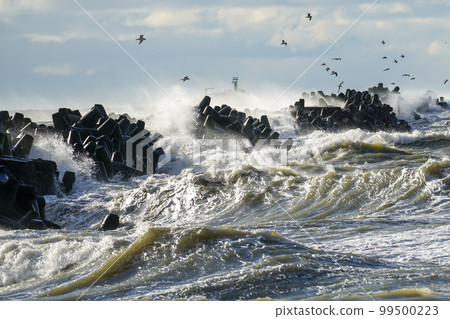 Coastal storm in the Baltic Sea, big waves crash against the harbor breakwater, breaking wave 99500223