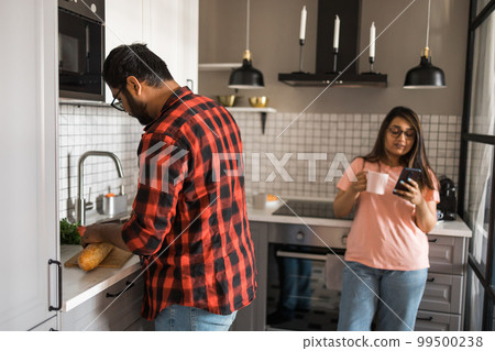Millennial couple in quarrel and woman with smartphone ignoring each other having breakfast together at home, gadget overuse - communication problem in family Millennial couple in quarrel and woman with smartphone ignoring each other having breakfast together at home, gadget overuse - communication problem in family 99500238