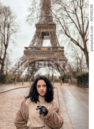 Lady near Eiffe Tower in Paris, France was made in winter. No snow, only some rain on the street. Lady near Eiffe Tower in Paris, France was made in winter. No snow, only some rain on the street. 99500286