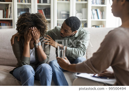 Loving black husband comforting crying wife while having family therapy 99500494