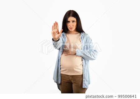 Strict young pregnant lady gesturing stop looking severely at camera forbidding or warning, white background Strict young pregnant lady gesturing stop looking severely at camera forbidding or warning, white background 99500641