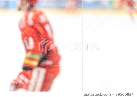 blurred view through protective glass. hockey player on the ice surface of the stadium 99500924