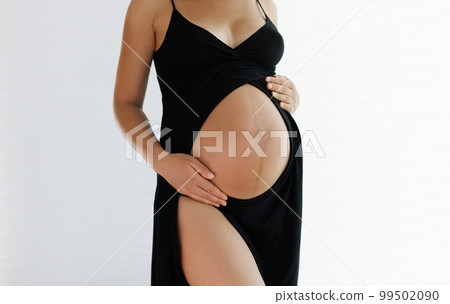 Pregnancy belly closeup. Pregnant woman elegant and beautiful wearing dress showing baby bump holding expecting tummy for skincare and health, lifestyle during pregnancy Pregnancy belly closeup. Pregnant woman elegant and beautiful wearing dress showing baby bump holding expecting tummy for skincare and health, lifestyle during pregnancy 99502090
