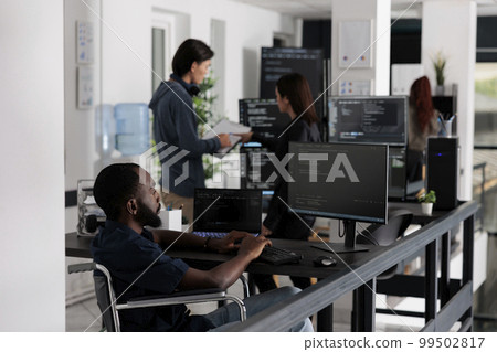 Disabled african american it engineer working on server program with computer, typing html code in coding office. web developer with chronic disability writing script with system algorithms. 99502817