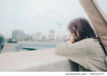 拿著吉他站在橋邊的女人的照片 99502977