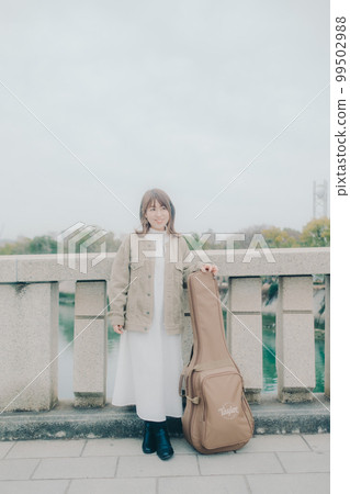 Photo of a woman holding a guitar standing by a bridge Photo of a woman holding a guitar standing by a bridge 99502988