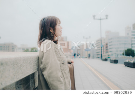 Photo of a woman holding a guitar standing by a bridge Photo of a woman holding a guitar standing by a bridge 99502989