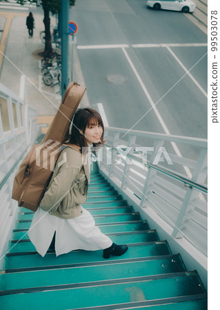 Photo of a woman holding a guitar standing on an overpass Photo of a woman holding a guitar standing on an overpass 99503078