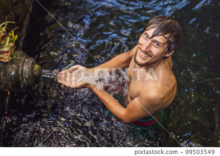 Man in holy spring water temple in bali. The temple compound consists of a petirtaan or bathing structure, famous for its holy spring water Man in holy spring water temple in bali. The temple compound consists of a petirtaan or bathing structure, famous for its holy spring water 99503549