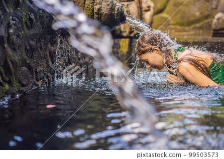 Woman in holy spring water temple in bali. The temple compound consists of a petirtaan or bathing structure, famous for its holy spring water Woman in holy spring water temple in bali. The temple compound consists of a petirtaan or bathing structure, famous for its holy spring water 99503573