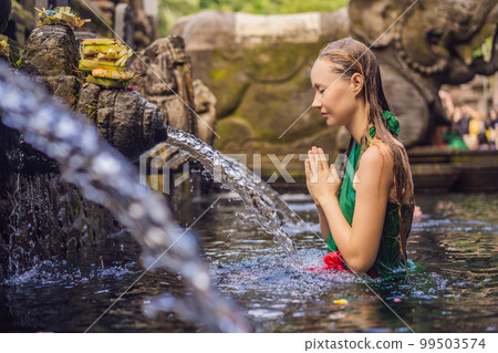 Woman in holy spring water temple in bali. The temple compound consists of a petirtaan or bathing structure, famous for its holy spring water Woman in holy spring water temple in bali. The temple compound consists of a petirtaan or bathing structure, famous for its holy spring water 99503574