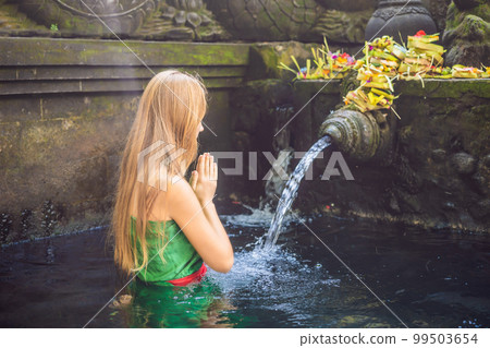 Woman in holy spring water temple in bali. The temple compound consists of a petirtaan or bathing structure, famous for its holy spring water Woman in holy spring water temple in bali. The temple compound consists of a petirtaan or bathing structure, famous for its holy spring water 99503654