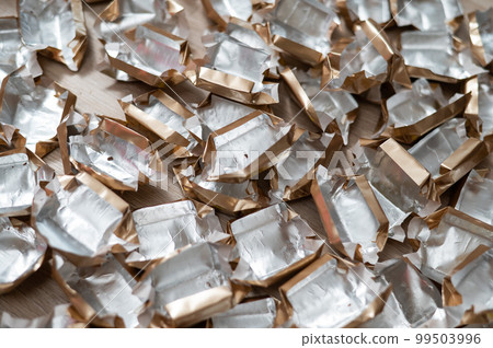 Pile of empty silver-gold candy wrappers. Top view.  99503996
