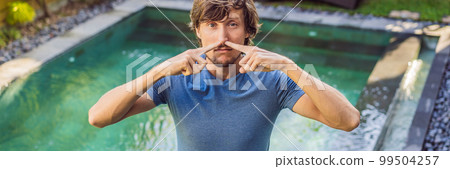 BANNER, LONG FORMAT Young man with disgust on his face pinches nose, something stinks, very bad smell in swimming pool because of pool chemicals. Negative emotion facial expression BANNER, LONG FORMAT Young man with disgust on his face pinches nose, something stinks, very bad smell in swimming pool because of pool chemicals. Negative emotion facial expression 99504257