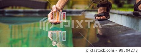 Pool worker checks the pool for safety. Measurement of chlorine and PH of a pool BANNER, LONG FORMAT 99504278